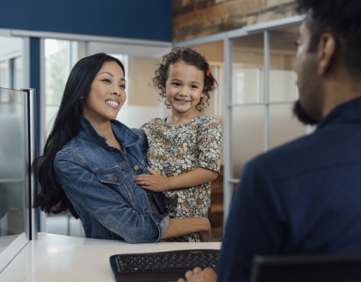 A woman wearing a jean jacket holds a child