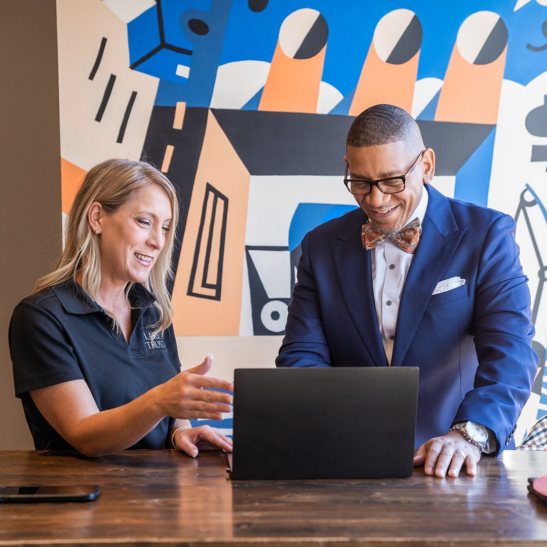 Ne'Gyle, the owner of Bleu Bowtique, looks at a laptop with a Lake Trust team member at a branch in Detroit