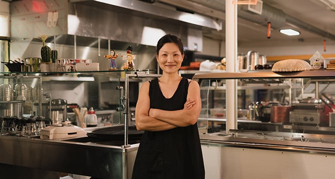 Maya, small business owner, stands proudly in her restaurant's kitchen.