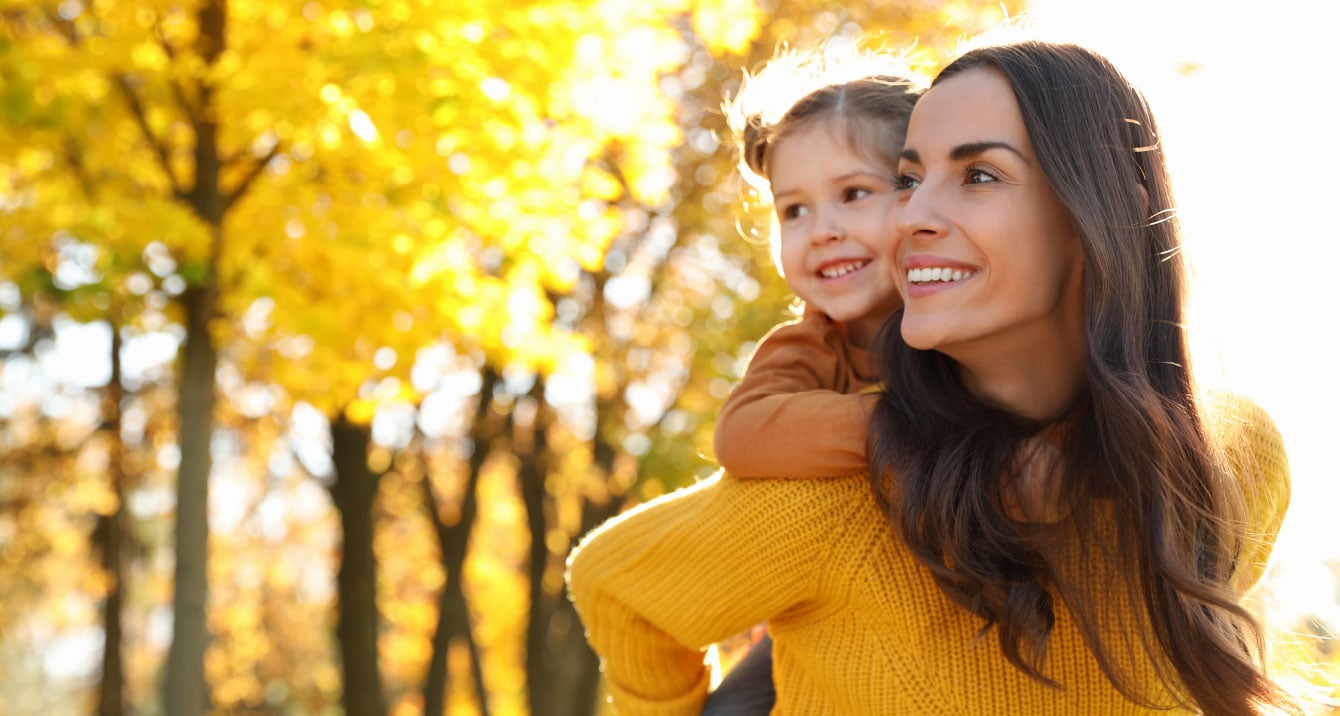 Woman with a child on her back walking in a forest