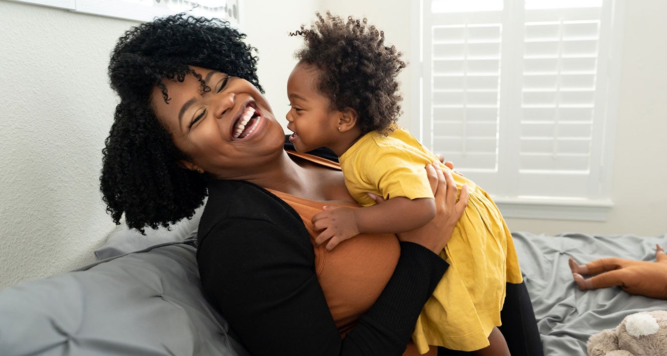 Mother and child laughing together in bedroom