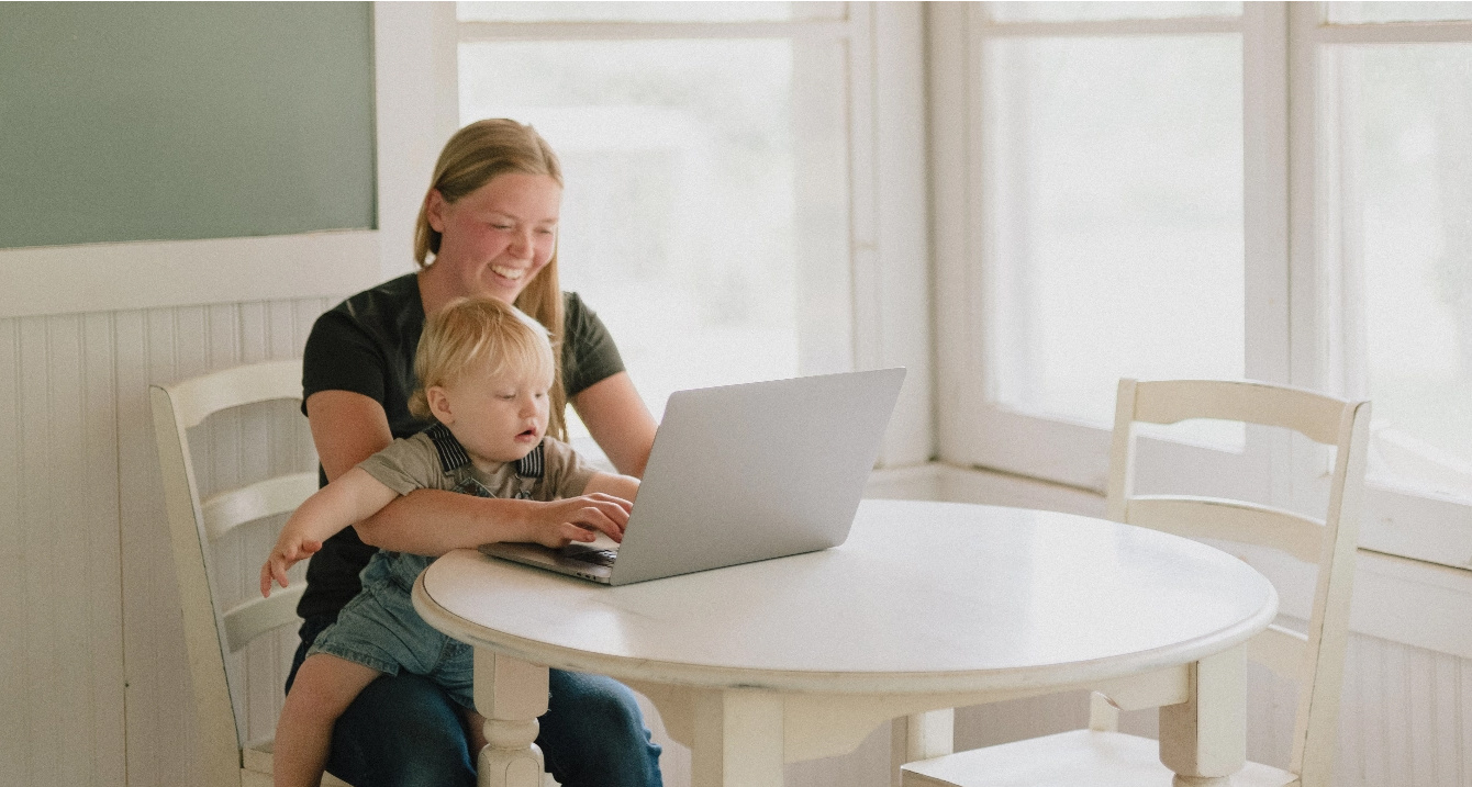 Mother and child smiling at computer screen.