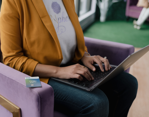 Person sitting in chair typing on laptop with Lake Trust Credit Card close by.