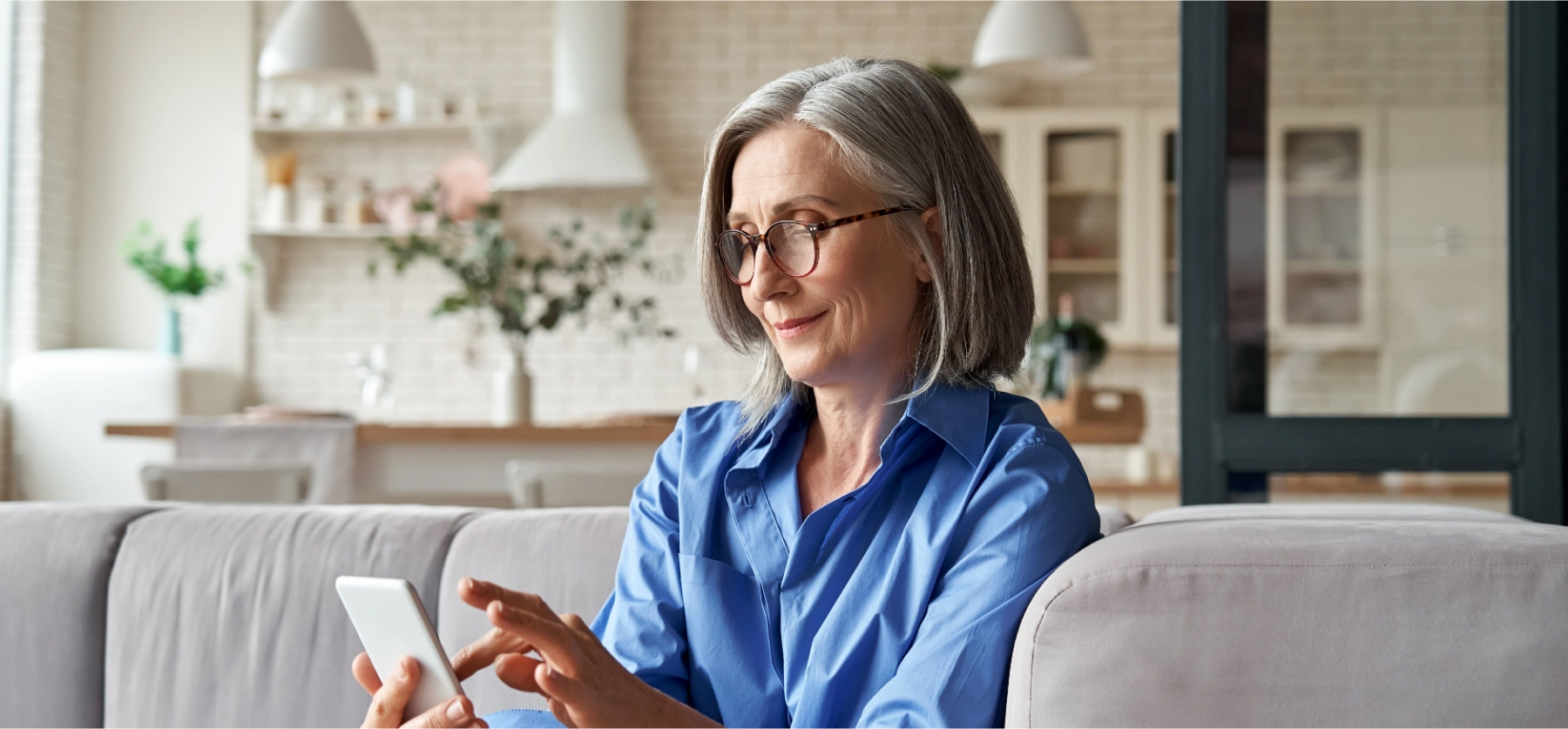 Woman sitting on couch scrolling on her cell phone.