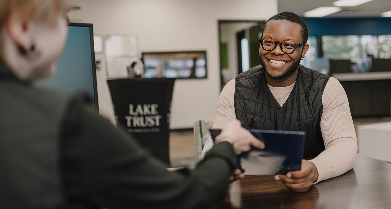 Lake Trust employee talking to a member in a branch at a desk.