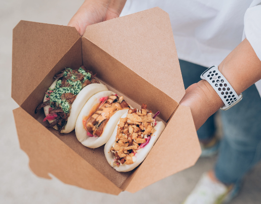 A close up of three bao buns in a food container