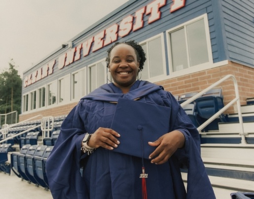 LaToya, a 2019 Lake Trust Foundation Scholarship recipient, wears a cap and gown and smiles in front of a Cleary University sign