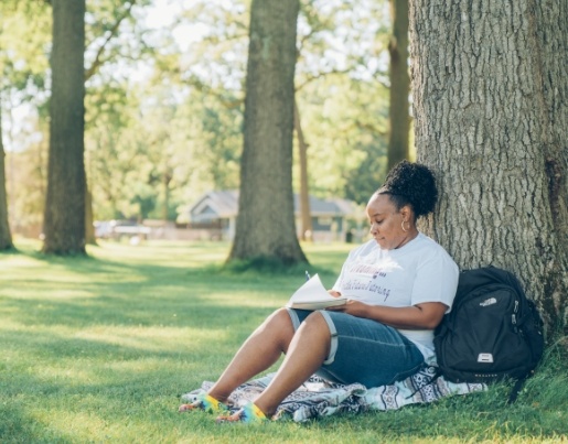 LaToya, a 2019 Lake Trust Foundation Scholarship recipient, sits against a tree and write in a notebook