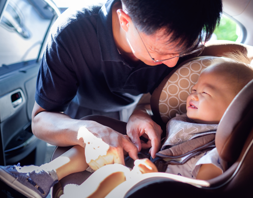 A man buckles a child into a car seat