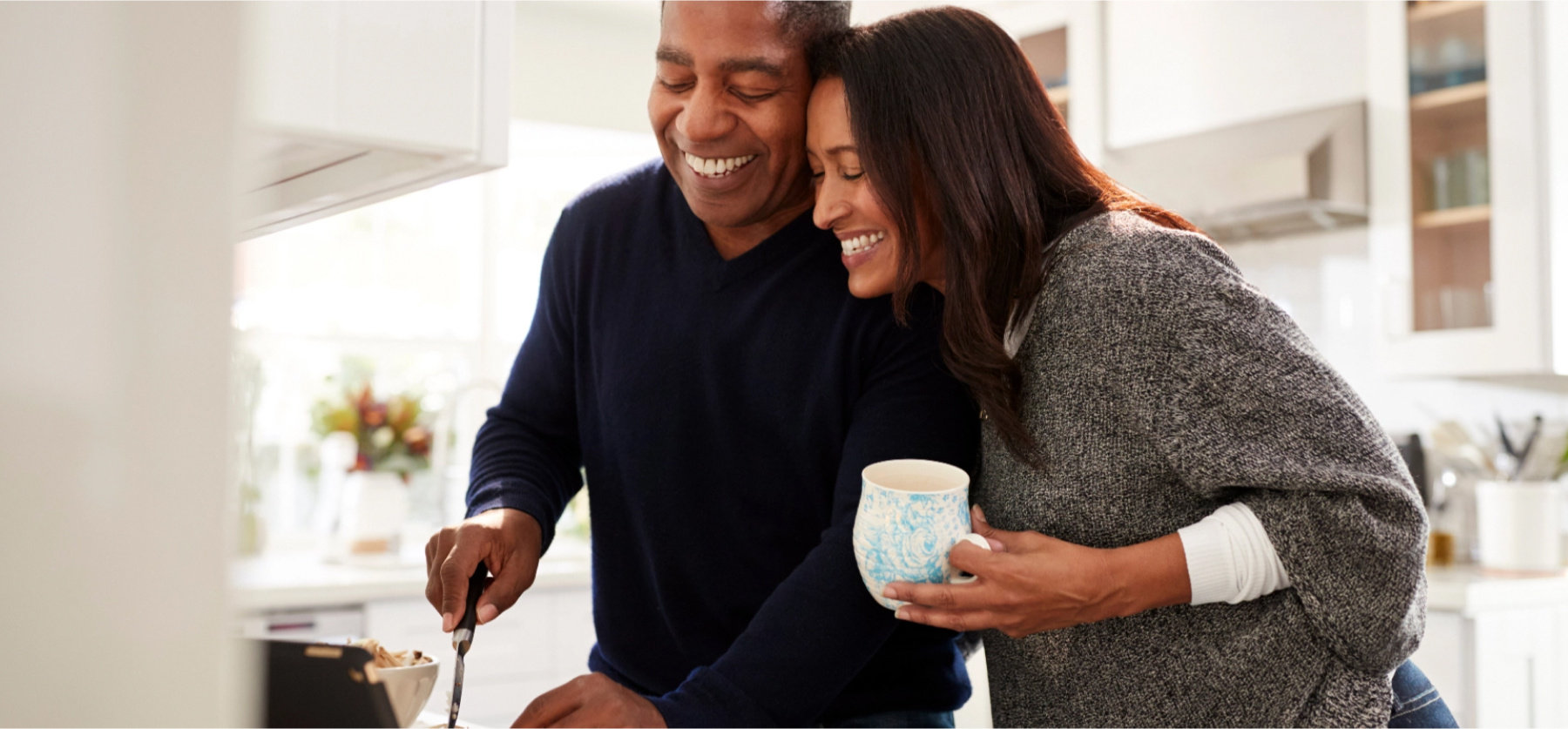 Couple laughing while cooking meal in kitchen