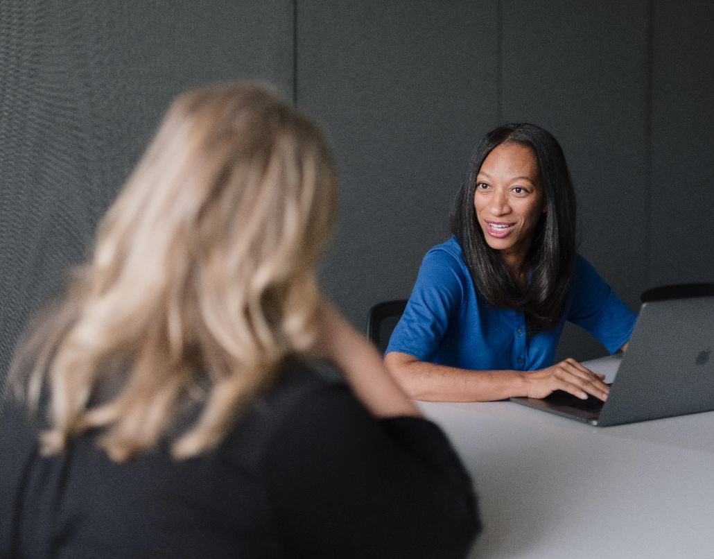 A Lake Trust team member sits in front of a laptop and talks to a person with long, blond hair