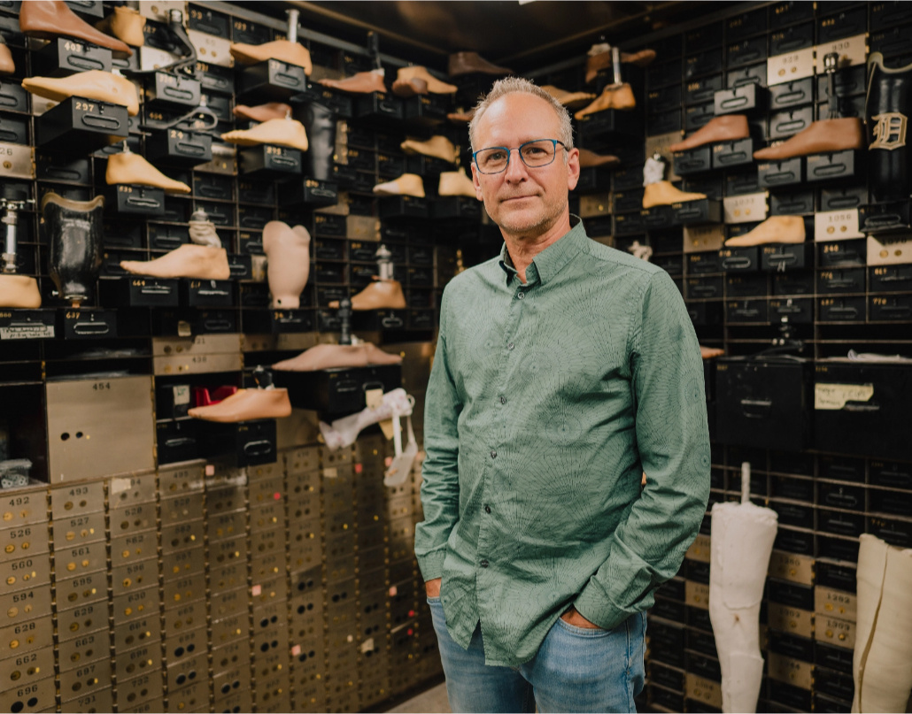 Chris, the owner of Anew Life Prosthetics and Orthotics, stands in front of prosthetic feet