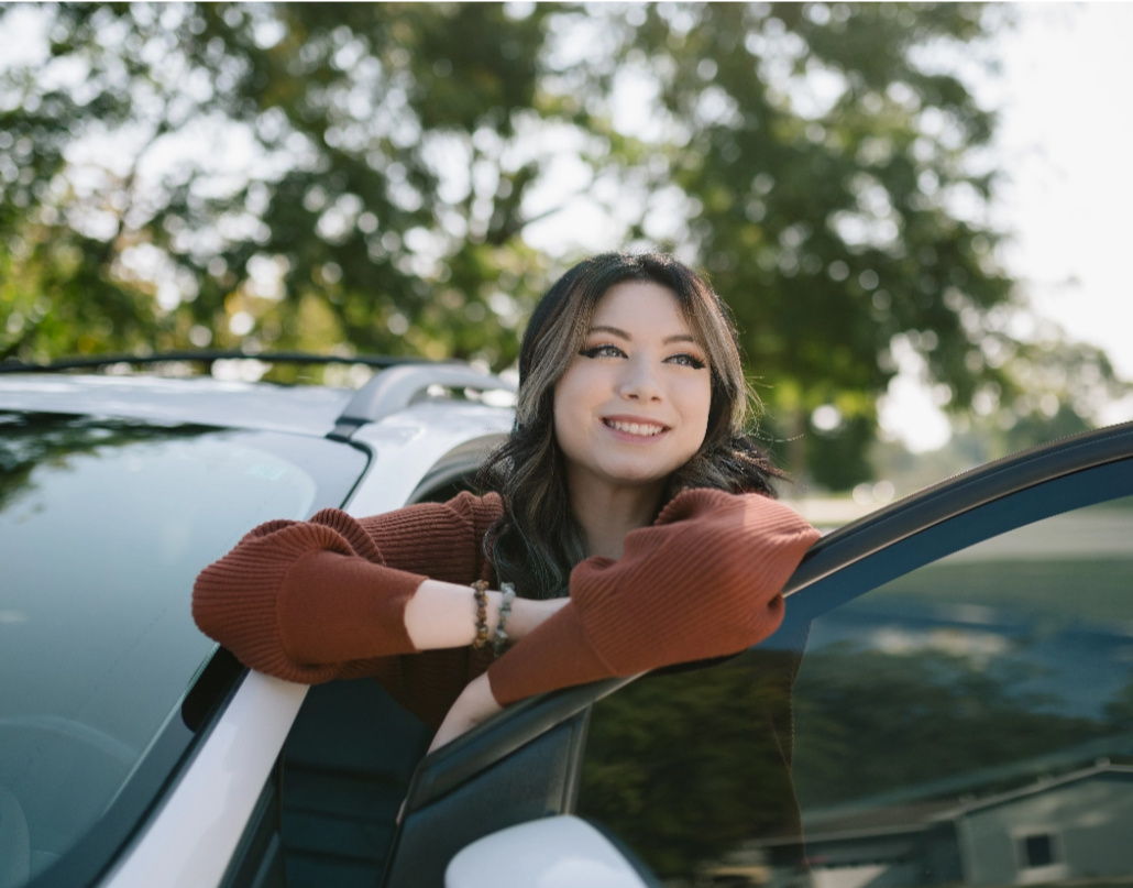 Kadence, a Lake Trust member, smiles next to the door of her SUV