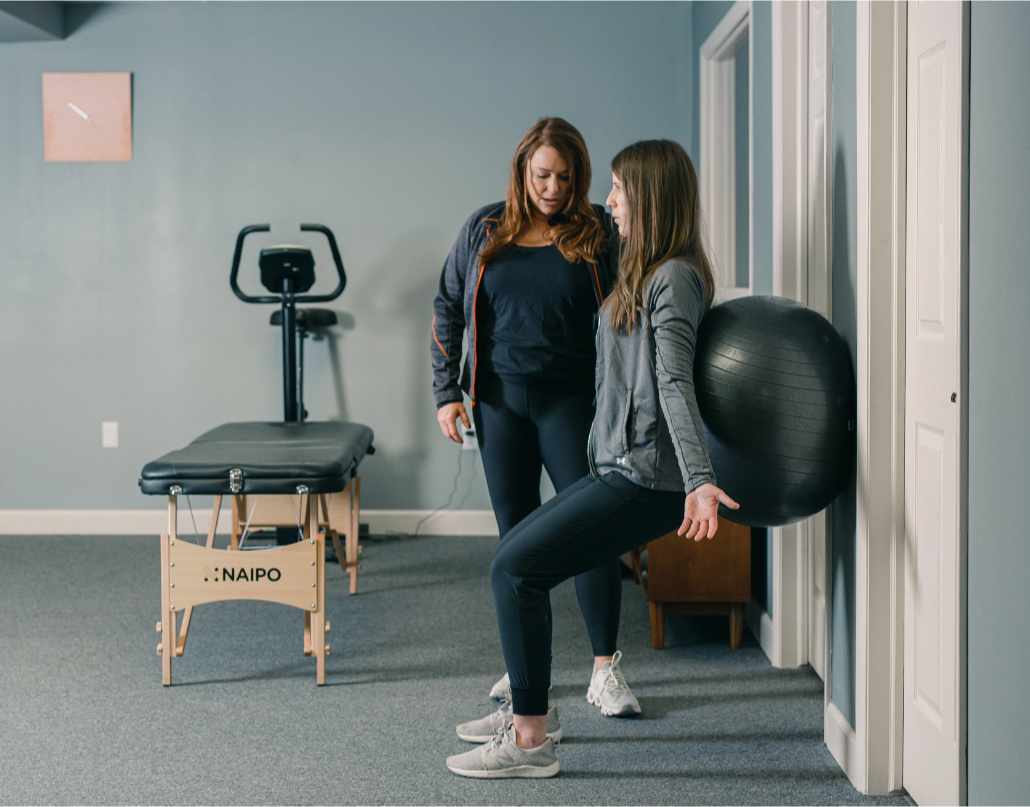 Amy, the owner of Peak Physical Therapy, instructs a client using an exercise ball