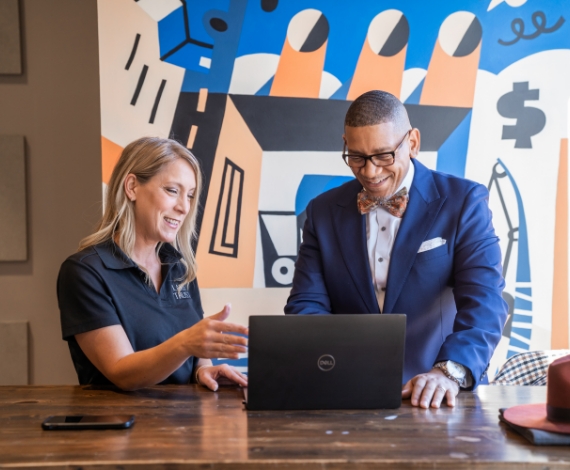 Ne'Gyle, the owner of Bleu Bowtique, looks at a computer screen with a Lake Trust team member