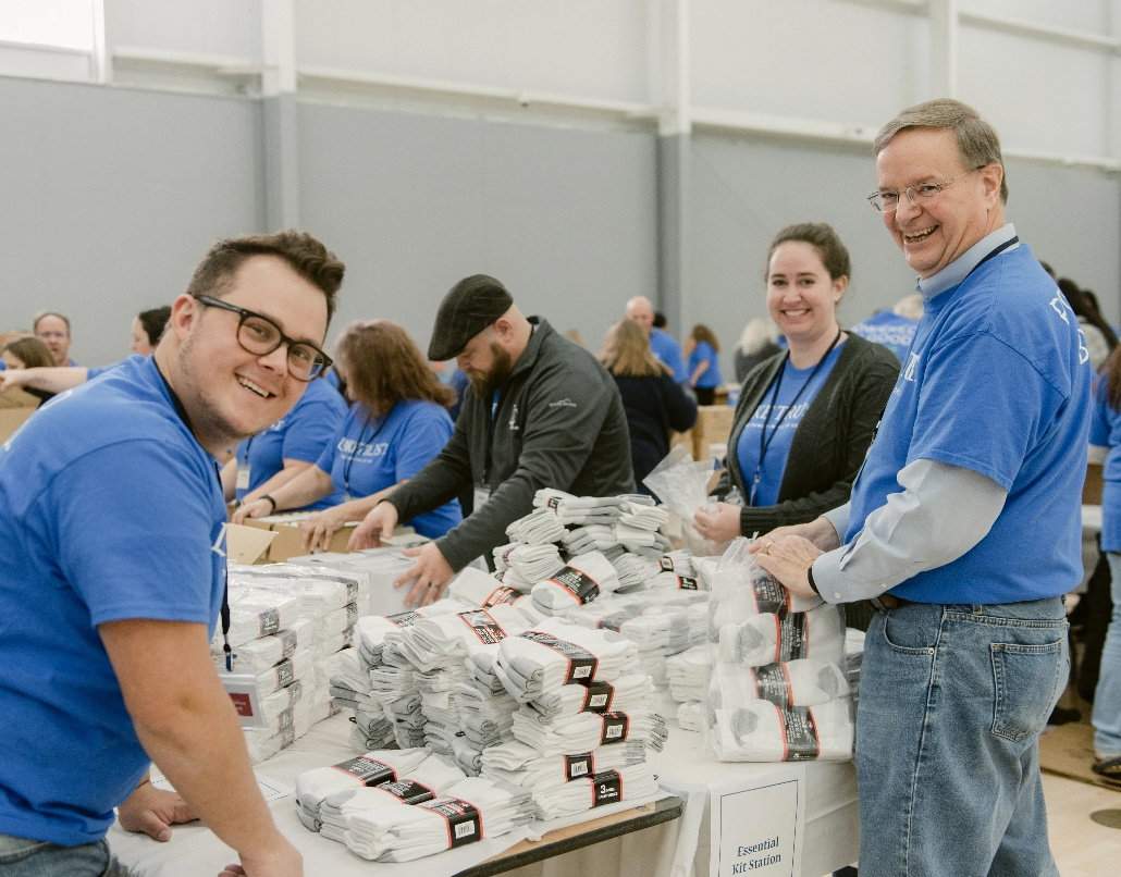 Three Lake Trust team members smile as they pack socks for a donation event