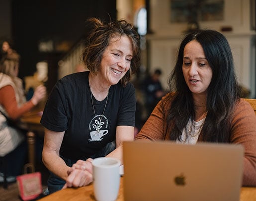 Two women looking at the same computer