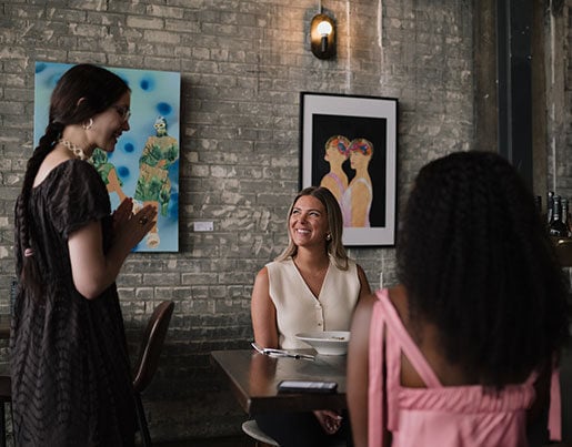 Freya waitress talking to two customers at a dining table