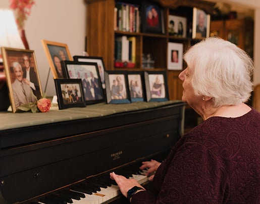 Georgia singing playing piano with pictures of her family on ledge. 