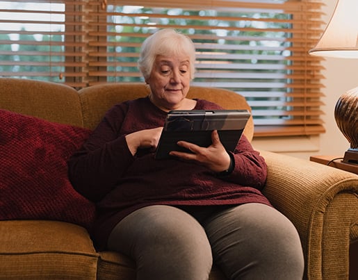 Georgia sitting on couch with her iPad. 