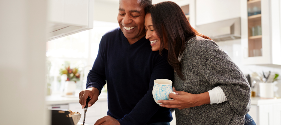 Couple laughing while cooking meal in kitchen