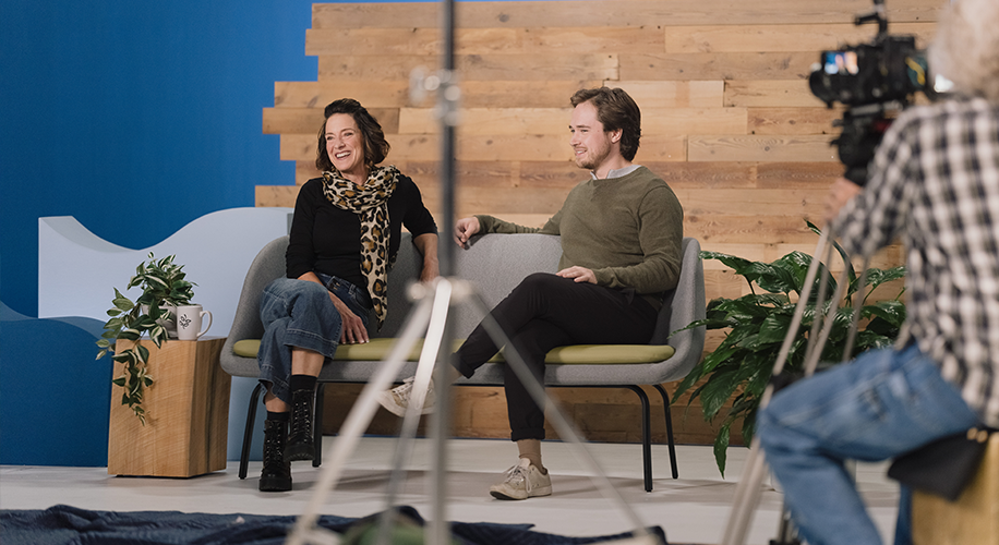 Amy and Spencer, the owners of Brighton Coffeehouse and Theater, sit on a couch in front of a wood wall