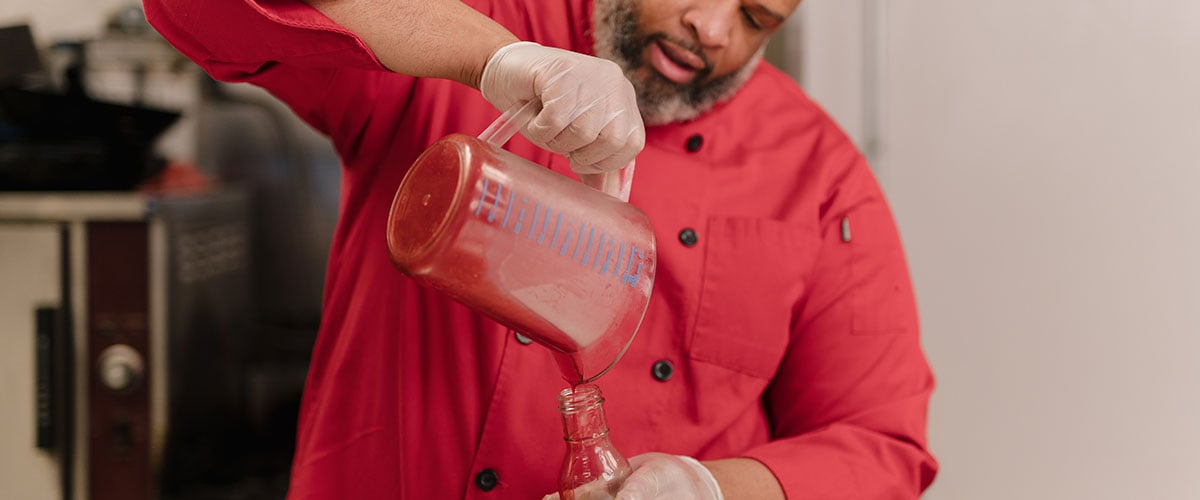 Marcus Leslie pouring strawberry sauce into a bottle.