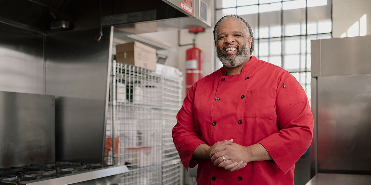 Marcus Leslie smiling standing in a kitchen.