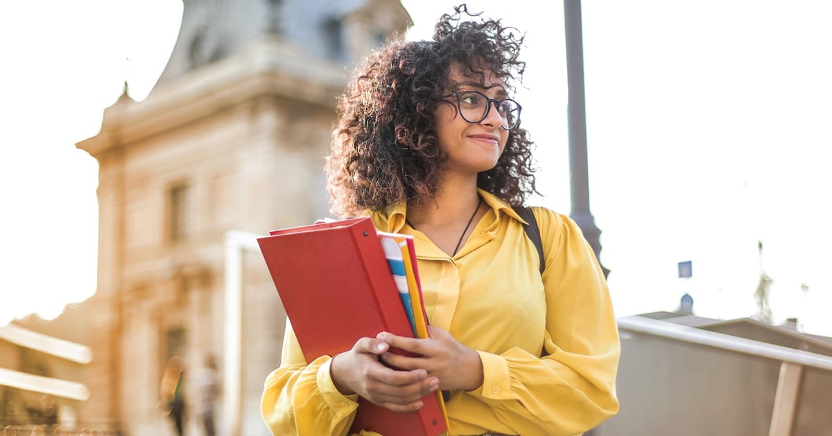 Student standing confidently holding books. 