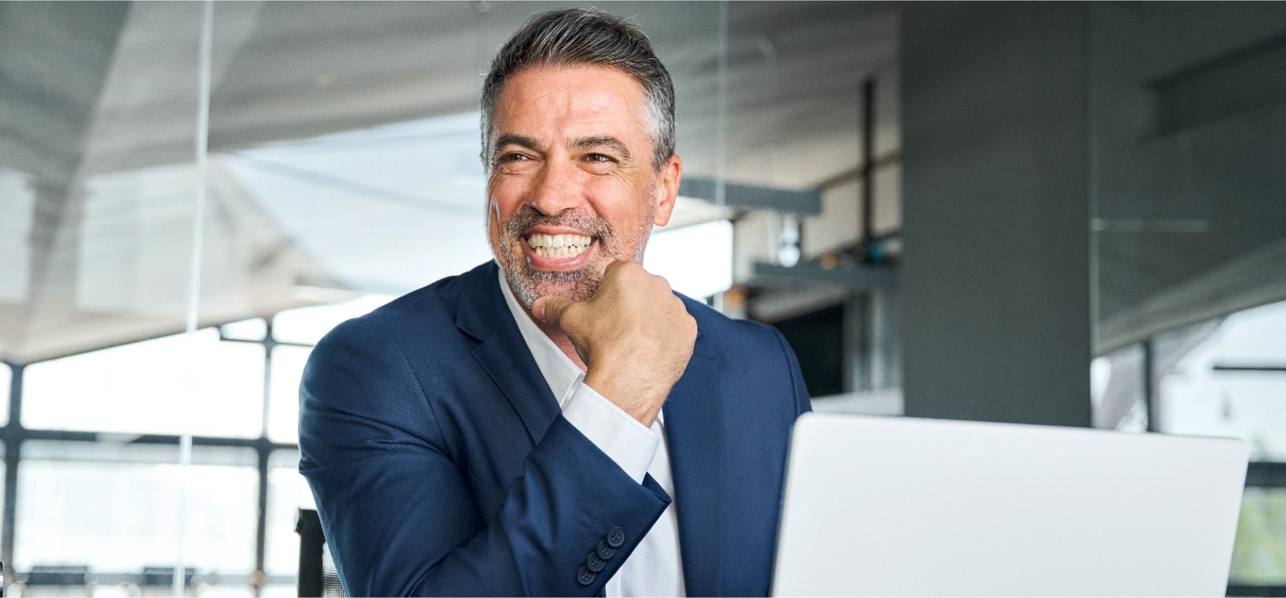 Smiling man in suit with open laptop