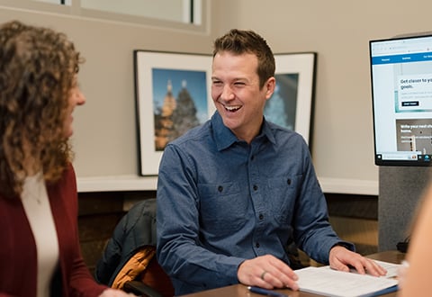 Corey, a Lake Trust member, sits at a desk, laughing