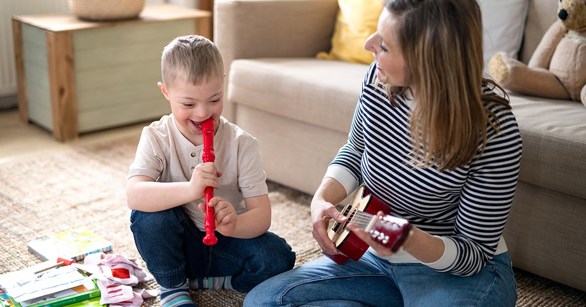 A young boy plays the recorder while a woman plays a ukulele 