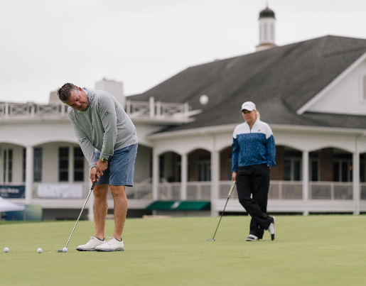 A man getting ready to putt at the Lake Trust Foundation Golf Outing and a woman in a baseball hat in the background