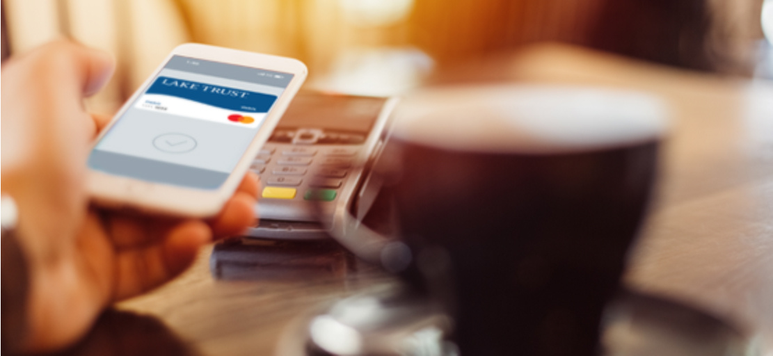 A person holds their phone with their digital wallet open to buy coffee