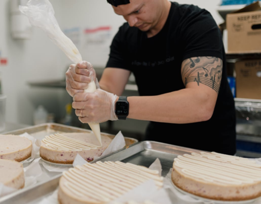 Baker making cheesecakes in incubator kitchen.