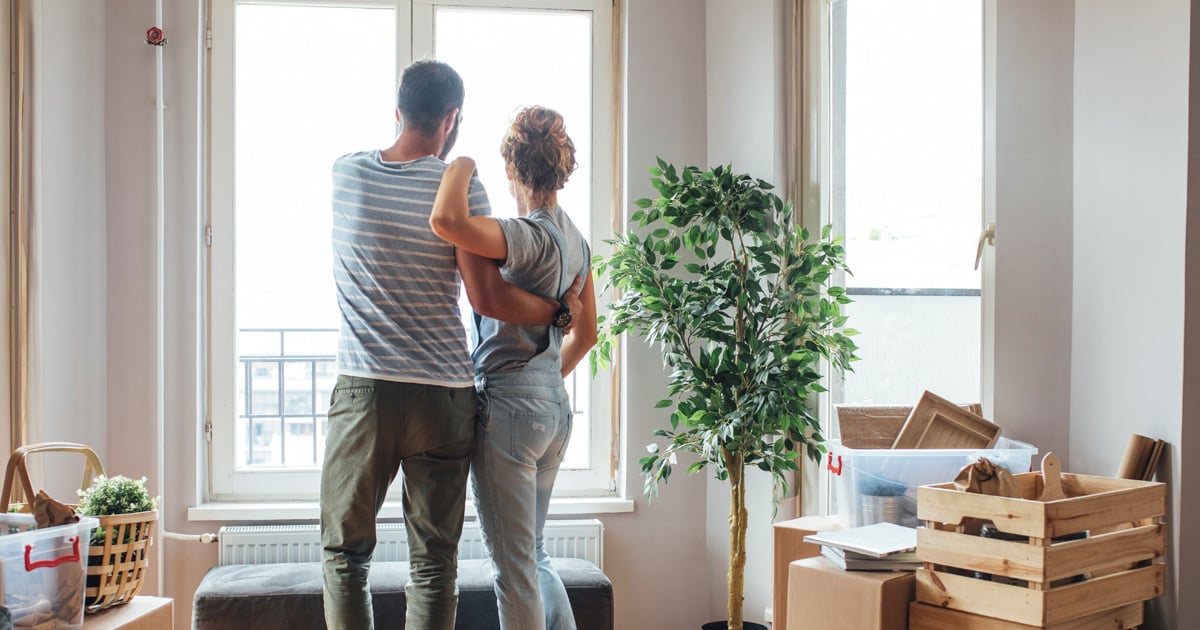 a man and woman looking out the window of their new home