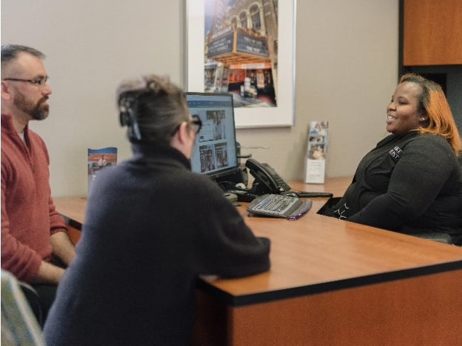 Tamiya, a Lake Trust team member, sits at a desk in front of two Lake Trust members