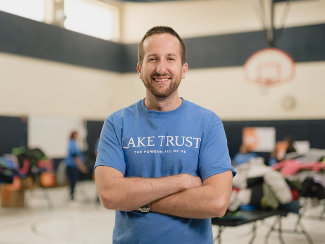 Ryan, a Lake Trust team member, wear a blue shirt that says "Lake Trust The Power In All of Us"