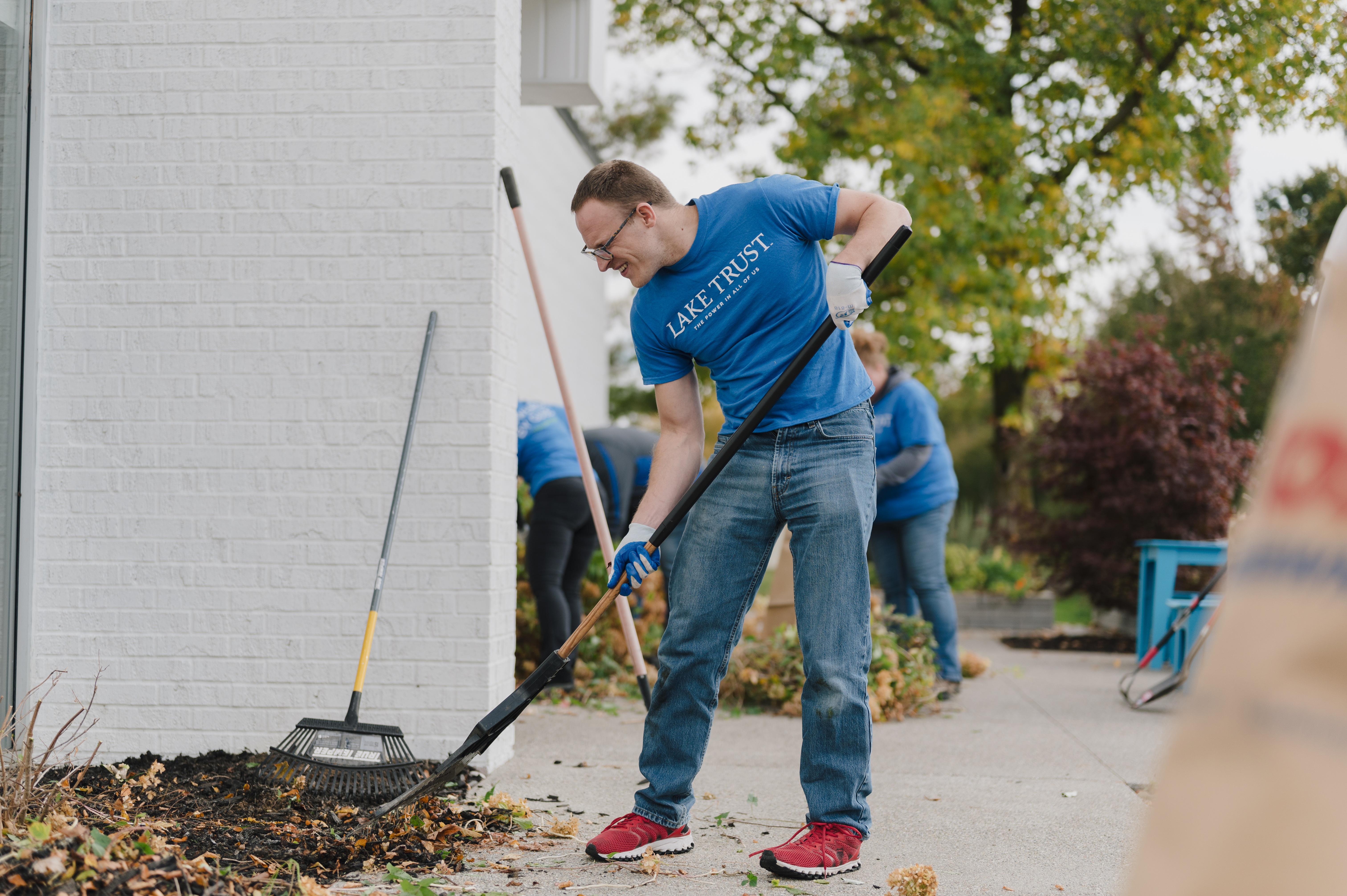 A Lake Trust team member raking an outdoor flowerbed.