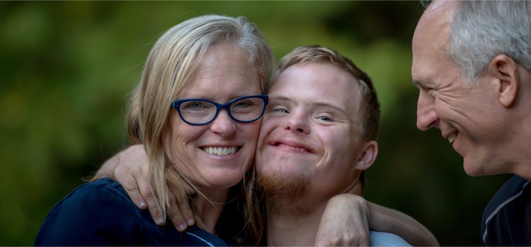 Mother and father with son, smiling and embracing. 