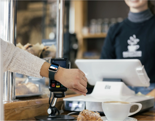 A person pays with their watch to buy a pastry and coffee at Brighton Coffeehouse