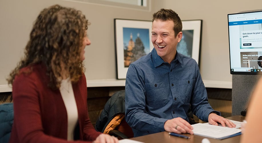 Corey, a Lake Trust member, wears a blue shirt and laughs with his wife in an office