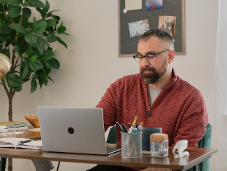 Michael, a Lake Trust member, sits at a desk and looks at a laptop