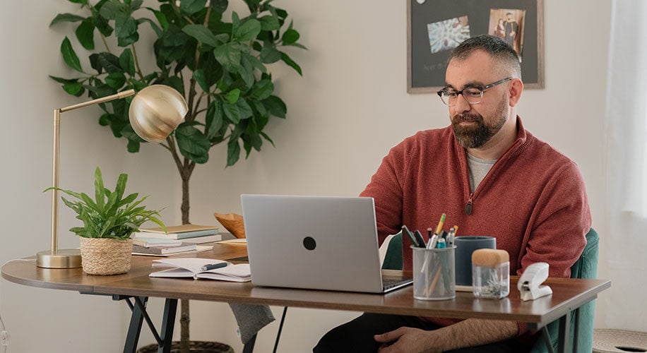 Michael, a Lake Trust member, sits at a desk and looks at a laptop screen