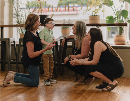 Nicole, the owner of More Love Collective, speaks to two women and a young boy in a yoga studio 