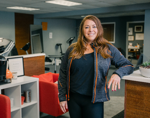 Amy, the owner of Peak Physical Therapy, smiles at the front of her office