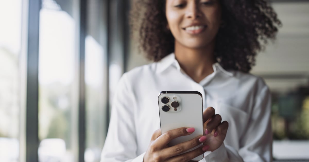 A woman in a white shirt texts on a phone