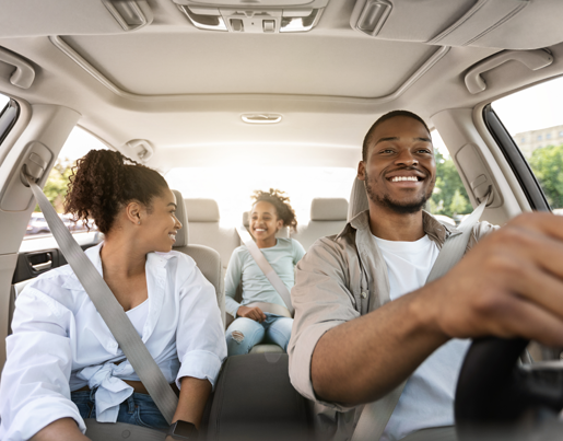 A man is driving a car and the woman sitting next to him looks in the back seat at a child in a car seat