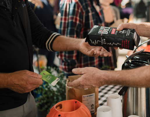 A person picks up a bag of Detroit Bold coffee and gives a Lake Trust credit card to a merchant