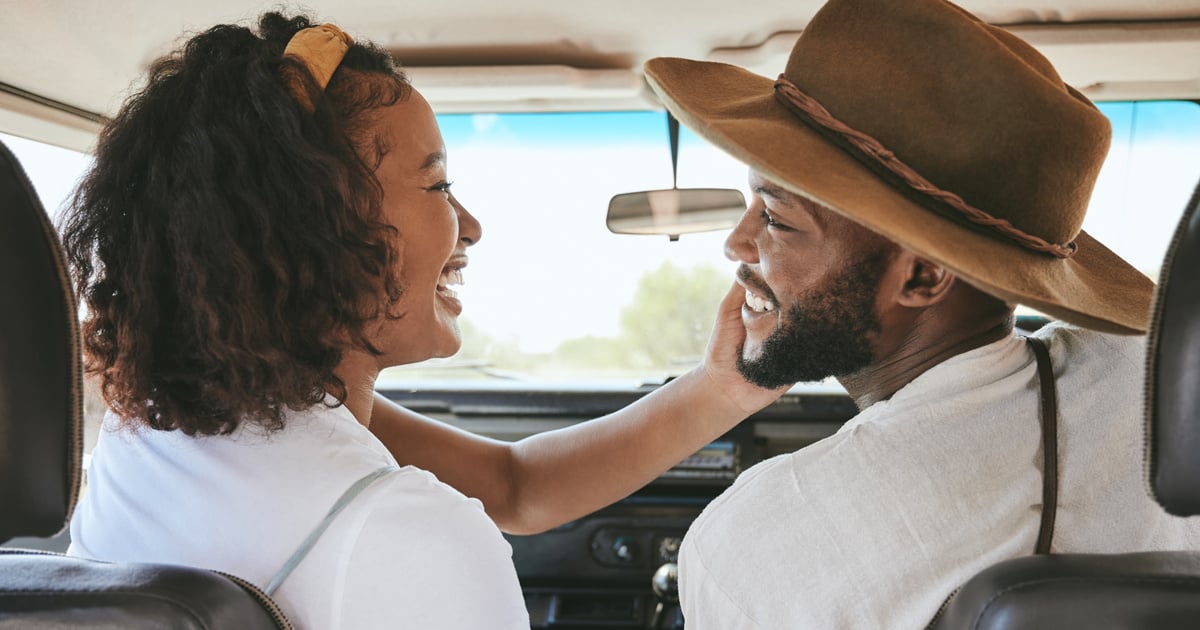 A woman puts her hand on a man's face in the front seat of a car